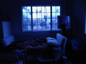 Outside: LA. Inside: a dark room with scrappy bed.