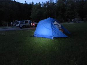A headlamp-lit tent in the evening hours.