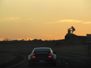 Silhouette of a winemaker standing above the sunset-lit highway
